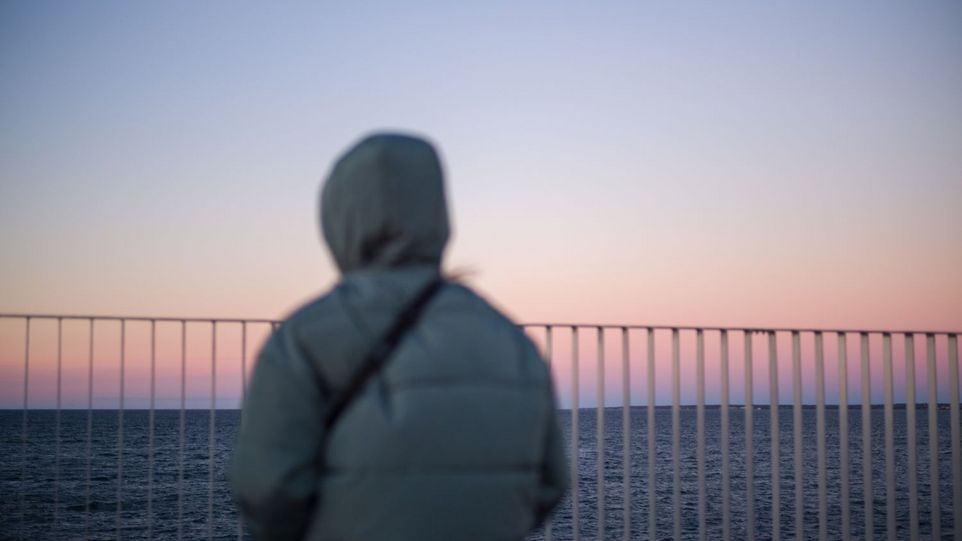 Rückansicht einer Person, die aufs Meer blickt