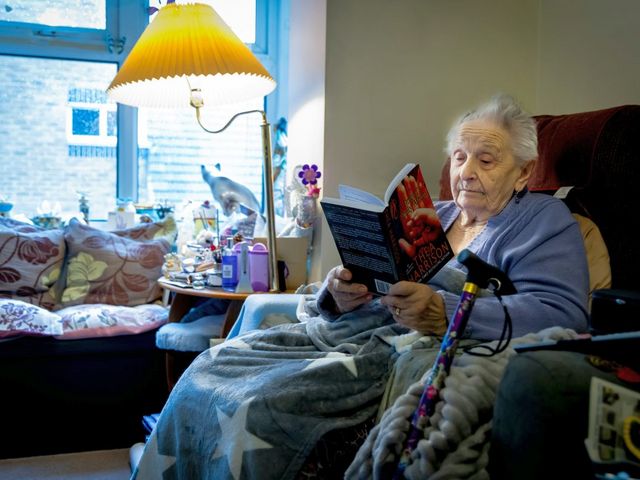 Lesende alte Frau im Sessel