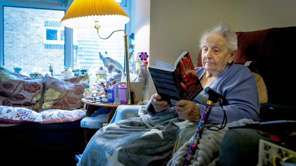 Lesende alte Frau im Sessel