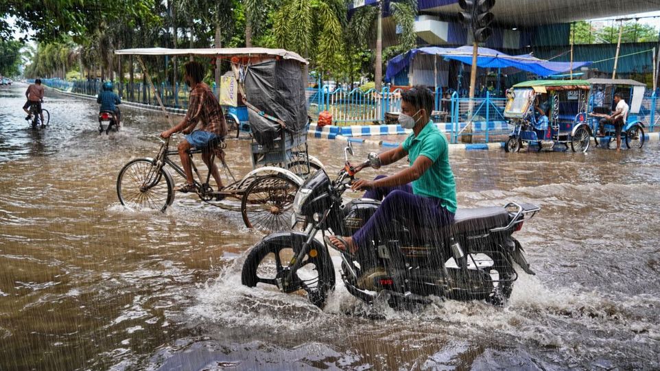 Rikschas und ein Motorrad auf einer überfluteten Straße in Kalkutta