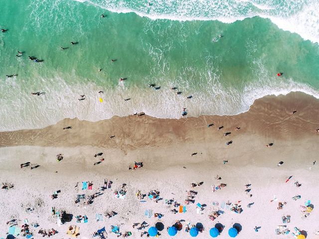 Luftansicht von einem Strand mit türkisem Wasser und Badenden