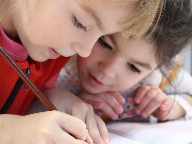 Zwei Mädchen beugen sich über ein Schulheft
