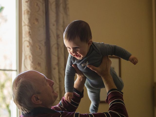 Älterer Mann hält Kleinkind in die Luft
