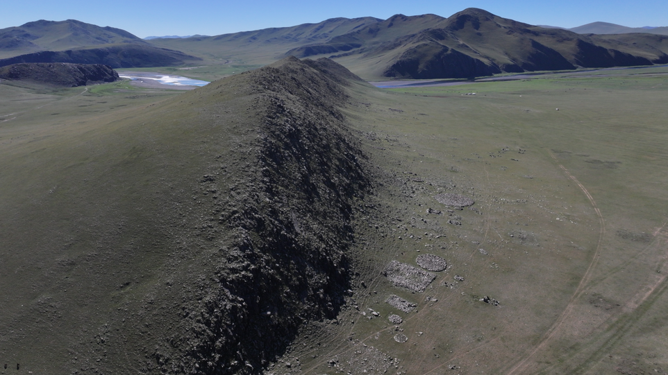 Berglandschaft mit Grabplatten am Fuß eines Bergkamms