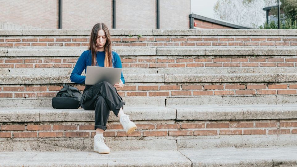 Junge Frau mit Laptop auf einer Treppe