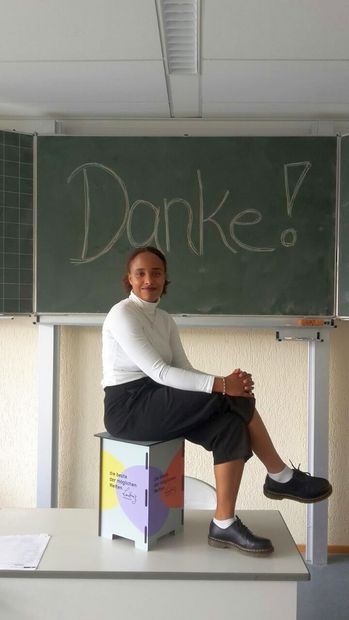 Shante Pasternack auf Leibniz-Hocker vor einer Tafel mit der Aufschrift "Danke"