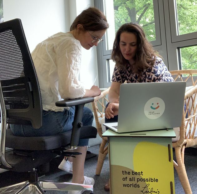 Zwei Frauen mit Laptop, der auf Leibniz-Hocker steht