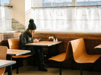 Junge Frau in einem leeren Restaurant, Blick auf ihr Smartphone