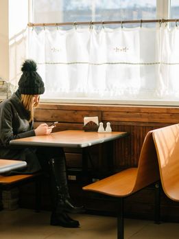 Junge Frau in einem leeren Restaurant, Blick auf ihr Smartphone