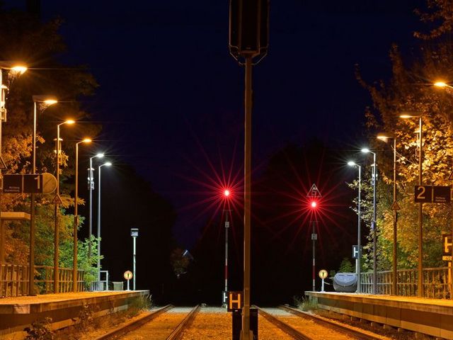 Nächtlicher Bahnhof mit beleuchteten Gleisen und roten Signalen