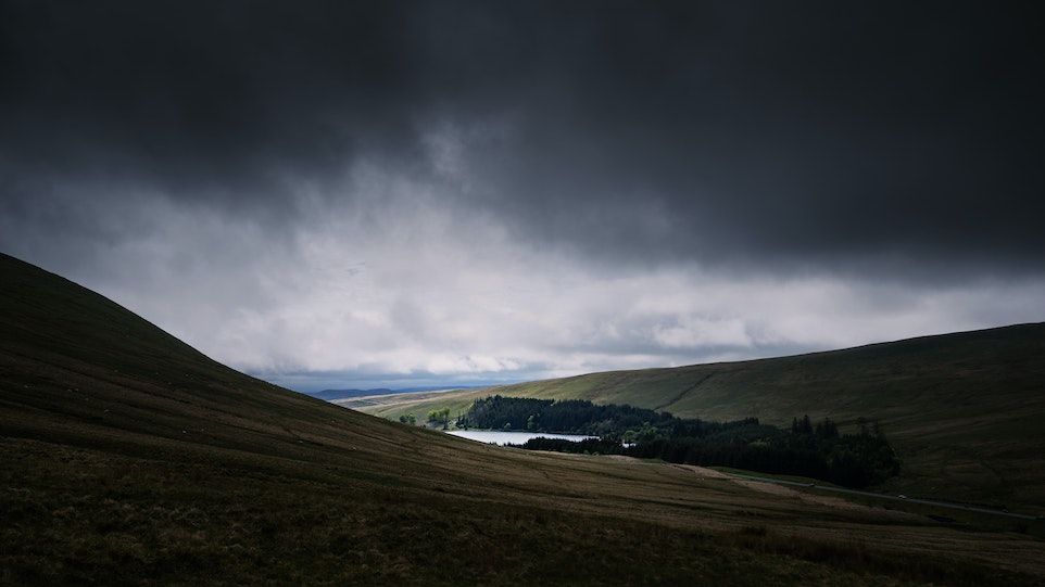 Dark rain clouds over hilly landscape