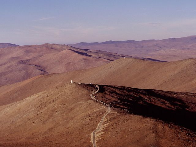 Kahle Berglandschaft mit einem Weg, der auf ein Gebäude in der Ferne zuläuft