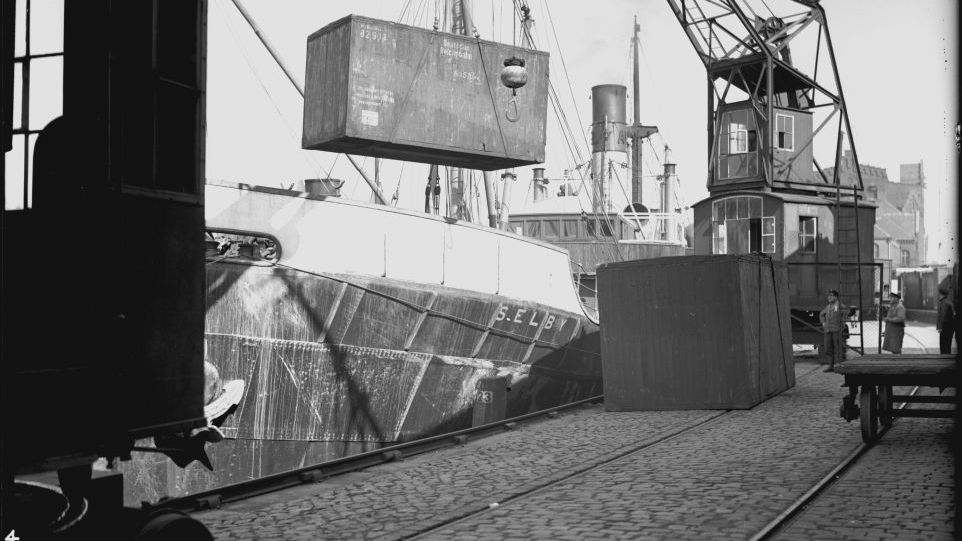 Black and white photo of the loading of a lift van onto a ship