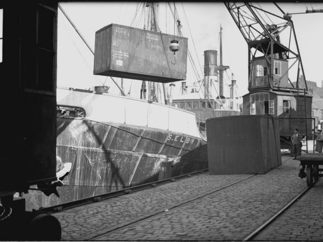 Black and white photo of the loading of a lift van onto a ship