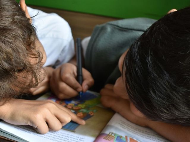 Zwei Jungen beugen sich über ein Schulbuch