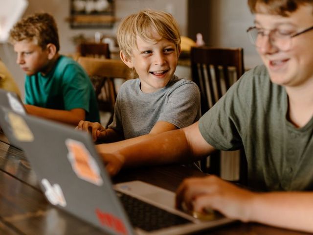 Vier Schüler mit Laptops an einem Holztisch