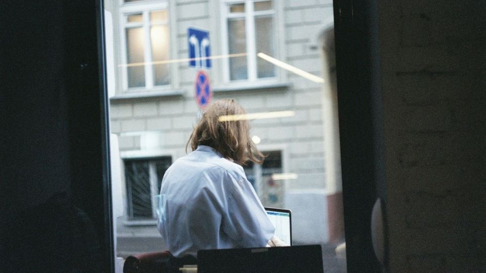 Frau am Laptop, durchs Fenster gesehen