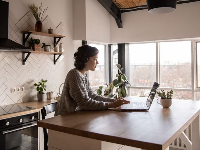 Woman working on the laptop at the kitchen table