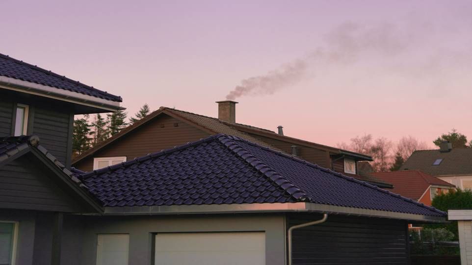 Einfamilienhaus im Abendlicht mit rauchendem Kamin