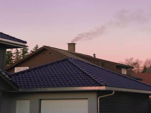 Einfamilienhaus im Abendlicht mit rauchendem Kamin