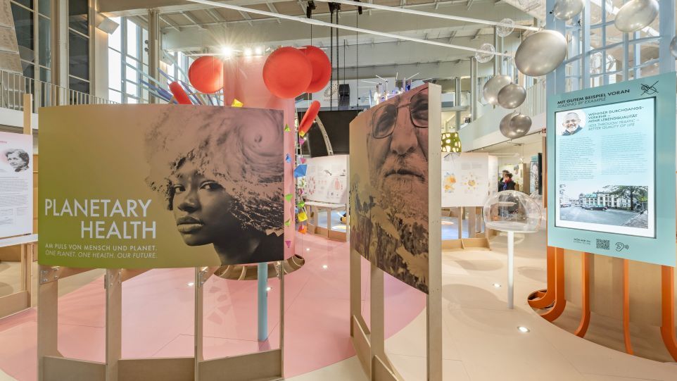 Ausschnitt des Ausstellungsraums "Planetary Health – Am Puls von Mensch und Planet" mit einem großformatigen Plakat im Vordergerund