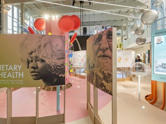 Ausschnitt des Ausstellungsraums "Planetary Health – Am Puls von Mensch und Planet" mit einem großformatigen Plakat im Vordergerund