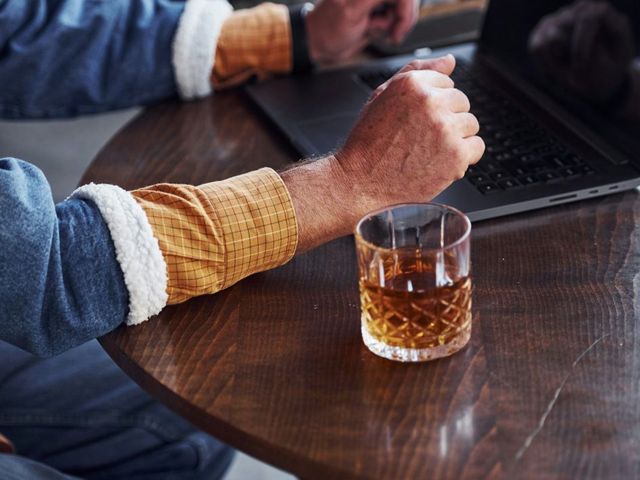 Glas Whisky neben Laptop