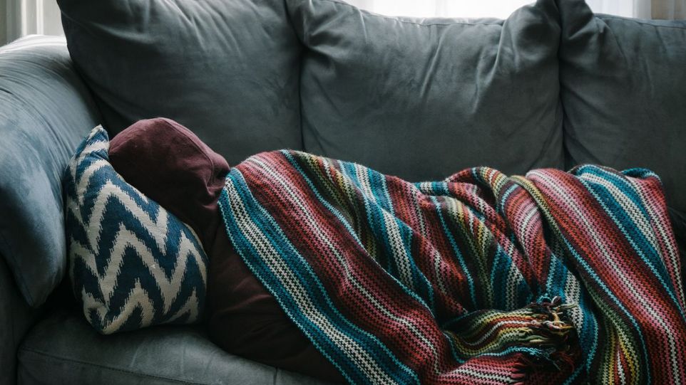 Rückenansicht einer auf dem Sofa liegenden Person