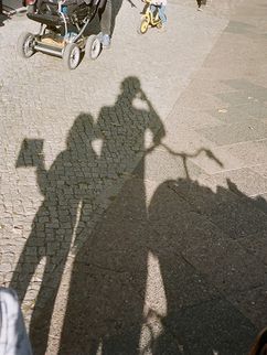 Agnes schaut auf die Schatten, die sie, ihr Vater und ihr Lastenrad auf die Straße werfen.