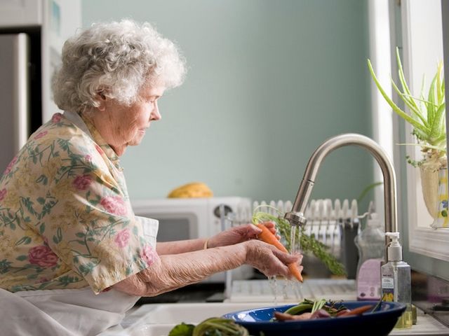 Ältere Frau wäscht Gemüse 