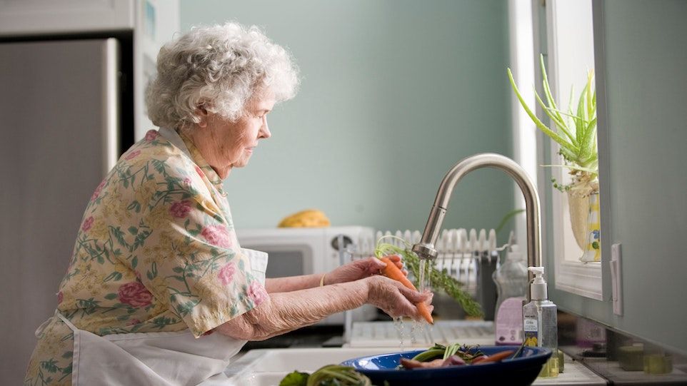 Ältere Frau wäscht Gemüse 