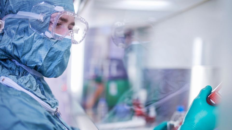 Neue Zelltherapien könnten zukünftig nicht nur bei Krebs, sondern auch bei Autoimmunerkrankungen wie der rheumatoiden Arthritis zum Einsatz kommen. Eine Person in Schutzkleidung arbeitet in eine Labor