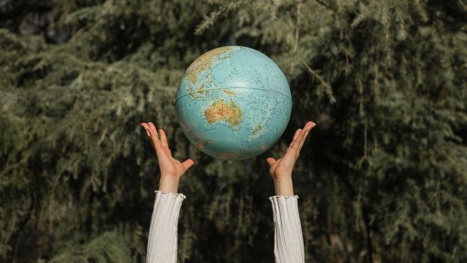 Hände, die eine Wasserball-Weltkugel in die Höhe werfen