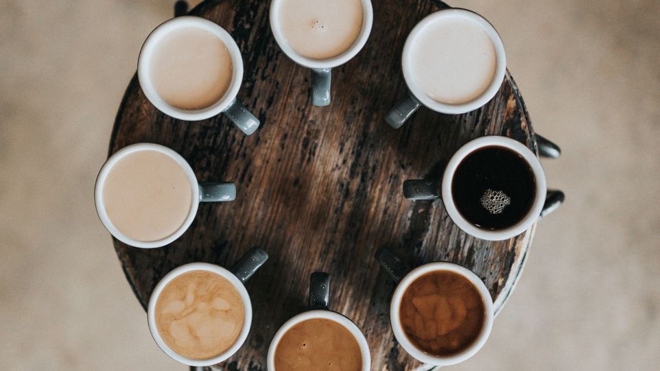 Acht Kaffeetassen gefüllt mit verschiedenen Kaffeearten