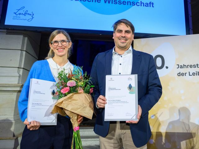 Preisträgerin und Preisträger mit Blumen und Urkunden