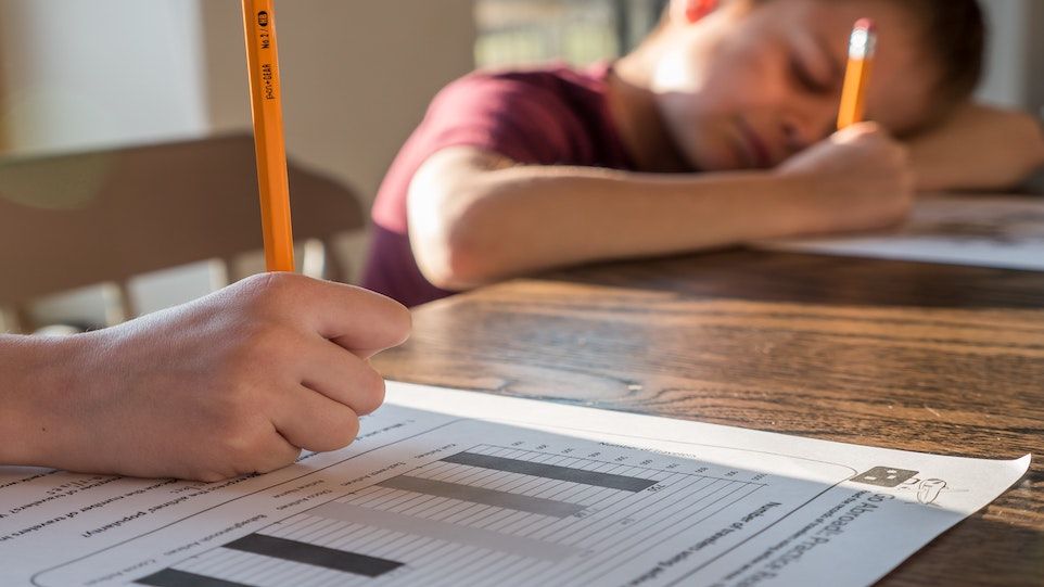 Nahaufnahme der Hand eines Kindes, welches Schulaufgaben bearbeitet