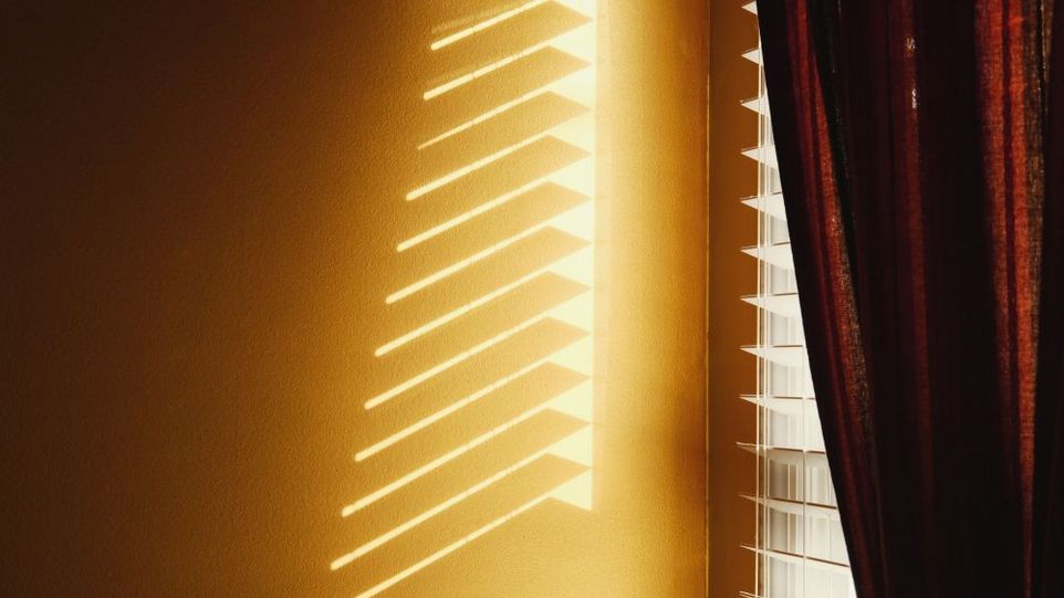 Sonnenlicht dringt durch Jalousie und Vorhang hindurch