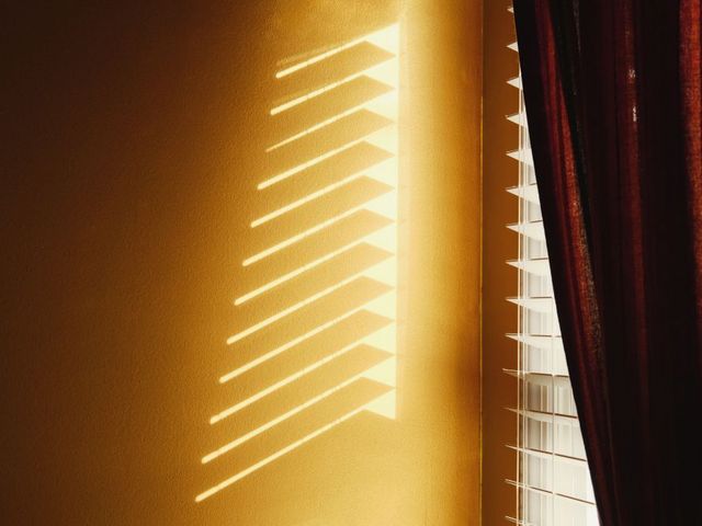 Sonnenlicht dringt durch Jalousie und Vorhang hindurch