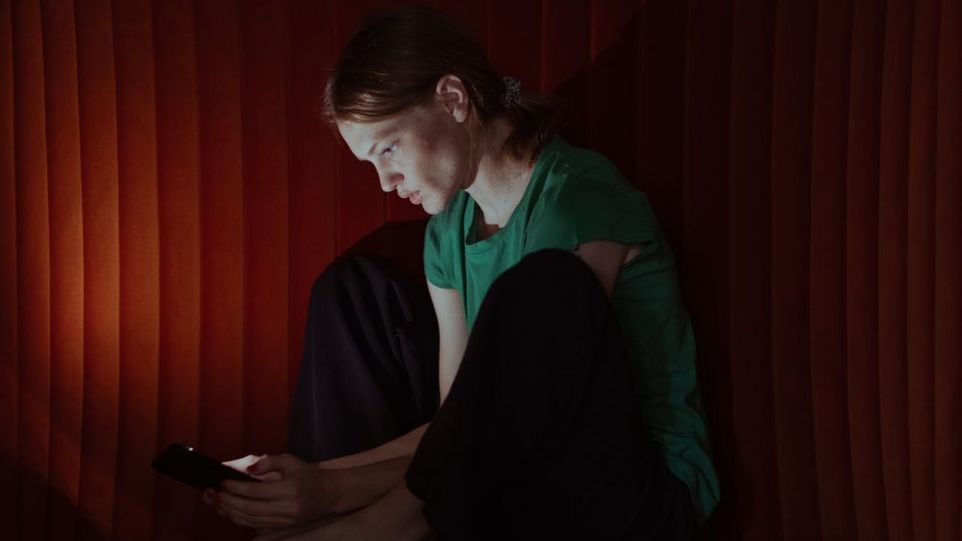 Junge Frau blickt gebannt auf ihr Smartphone.