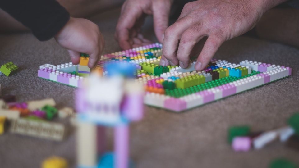 Kinder und Männerhände, mit Lego spielend 