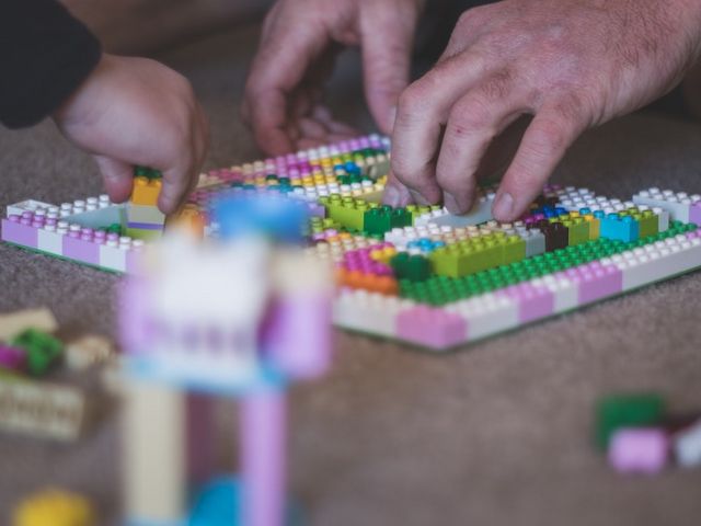 Kinder und Männerhände, mit Lego spielend 