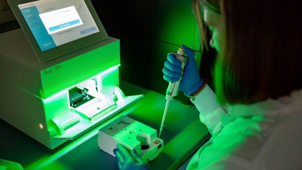 Vorbereitung der Proben im Labor für die Genomsequenzierung Wissenschaftlerin mit Pipette vor Genomsequenzierungs-Apparat